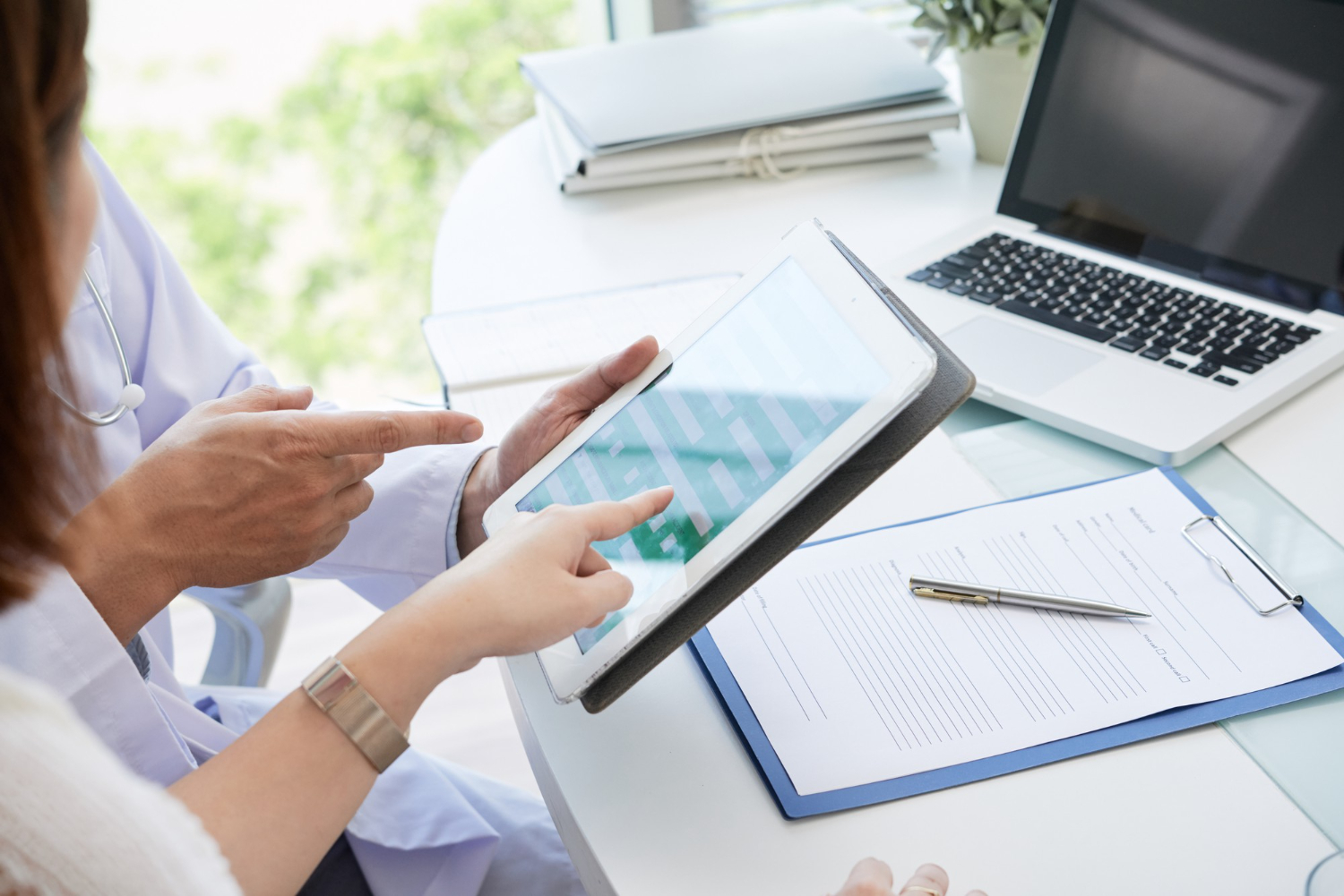 Doctor explaining patient how to fill personal data in form on digital tablet