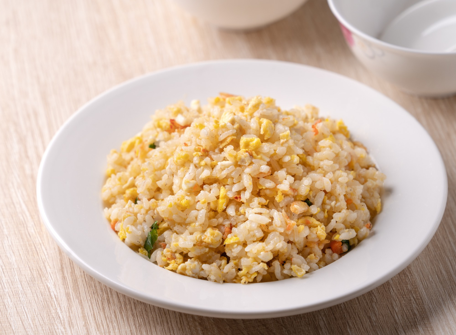 Close up of Chinese fried rice with sergestid Sakura shrimp in white plate on bright wooden table background