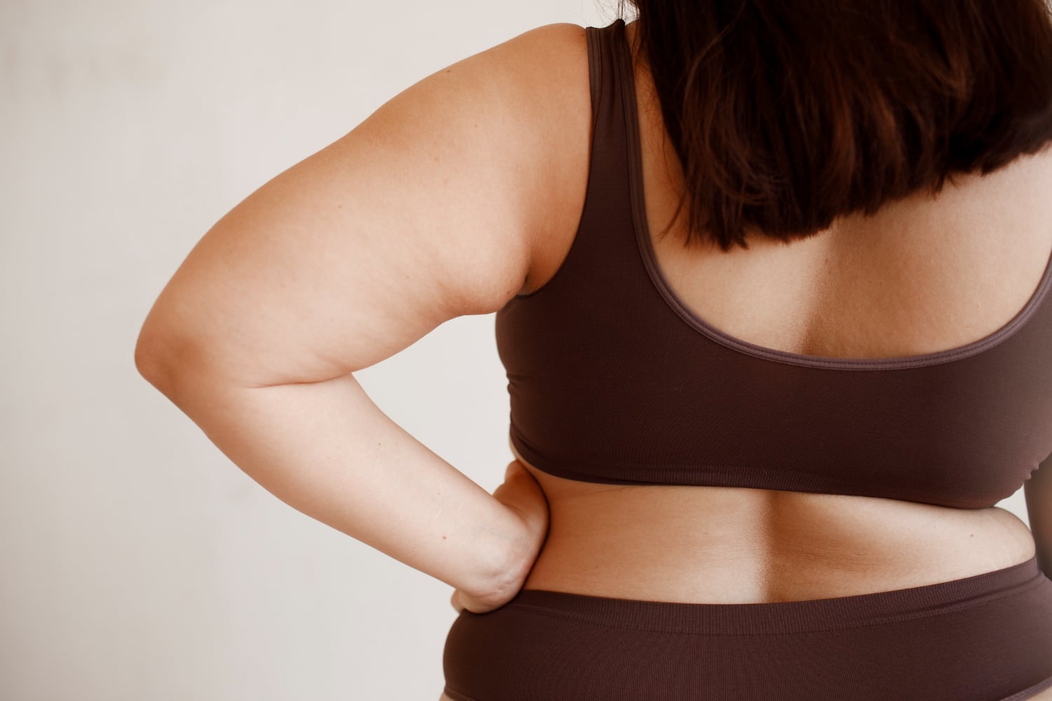 Back view plus size woman posing in studio
