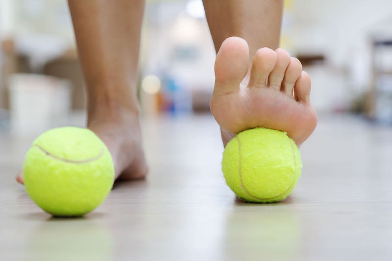 一顆網球就可自助按摩足底筋膜,鬆筋膜又能刺激淋巴循環:雙腳踩住網球來回推動,從腳趾推到腳跟,來回滾動約1分鐘,接著換腳再做一次即可。
